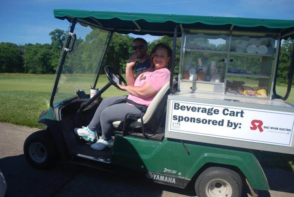 Two people smiling and waving from the beverage cart